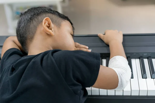 Un asiático chicos en las manos heridas son dormir en el piano . — Foto de Stock