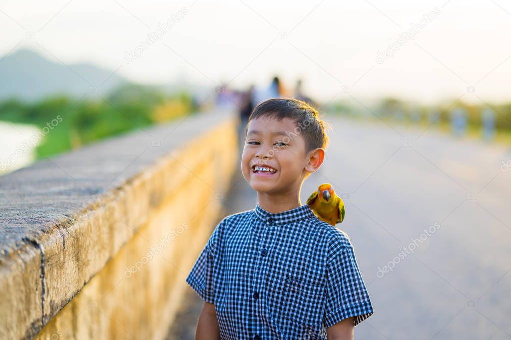 The boy playing with the parrot on his shoulders.