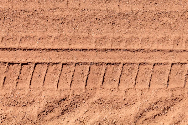 Texture of Track Tire Engraved in Reddish Dirt Road