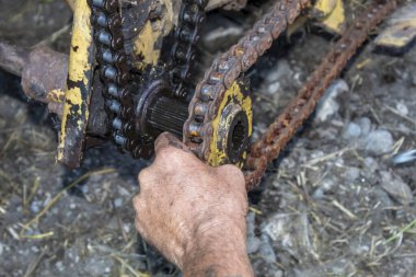 Erkek El, Çapa Hasatçısı 'nı tamir ederken Sprocket Wheel' e zincir takmaya çalışıyor.