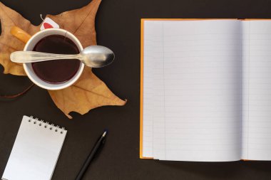 Kompozisyon Oluşturuldu Teacup, Kuru Sonbahar Yaprağı, Tatkaşığı, Küçük Açık Boş Not Defteri, Kalem ve Orange Open Boş Not Defteri