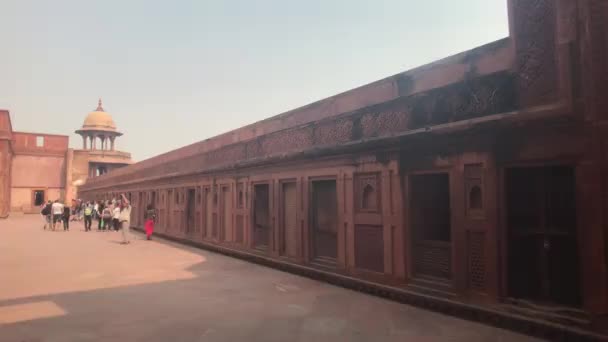 Agra, India, 10 november 2019, Agra Fort, toeristen lopen langs de rode bakstenen structuur — Stockvideo
