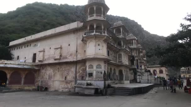 Jaipur, India, 04 de noviembre de 2019 Galta Ji, turistas pasan contra el telón de fondo de un antiguo edificio de esquina — Vídeo de stock