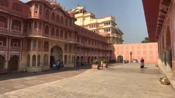 Jaipur, Indie - 4. listopadu 2019: Turisté z Městského paláce kráčejí na pozadí budovy s růžovými zdmi — Stock video