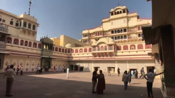 Jaipur, Indie - 4. listopadu 2019: Turisté z Městského paláce stojí ve stínu budovy — Stock video