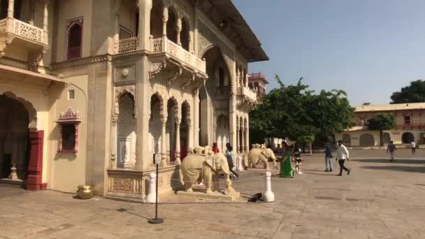 Jaipur, India - 04 de noviembre de 2019: Los turistas del City Palace entran en un edificio con elefantes a la entrada — Vídeos de Stock