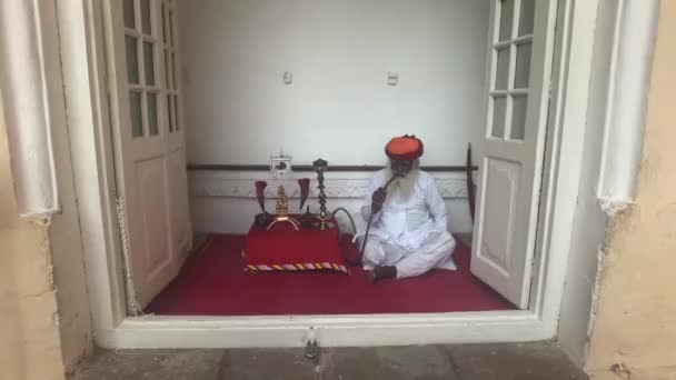 Jodhpur, India - 06 de noviembre de 2019: Mehrangarh Fort viejo turista se sienta descansando y fuma una pipa — Vídeo de stock