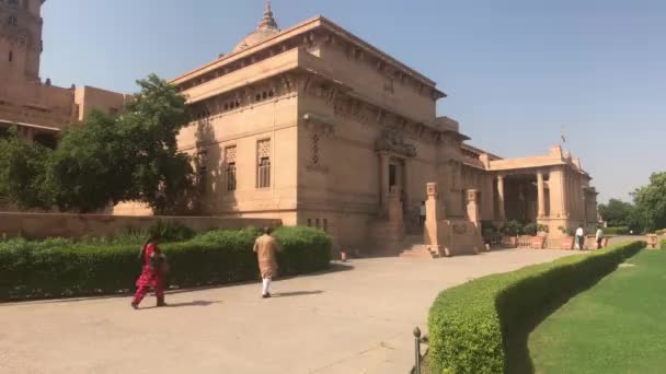 Jodhpur, India - November 06, 2019: Umaid Bhawan Palace tourists pass by neat buildings — Stock Video