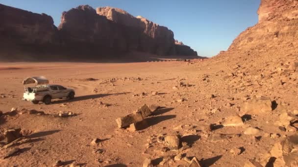 Wadi Rum, Jordanië - rood zand in de woestijn tegen de achtergrond van rotsachtige bergen — Stockvideo