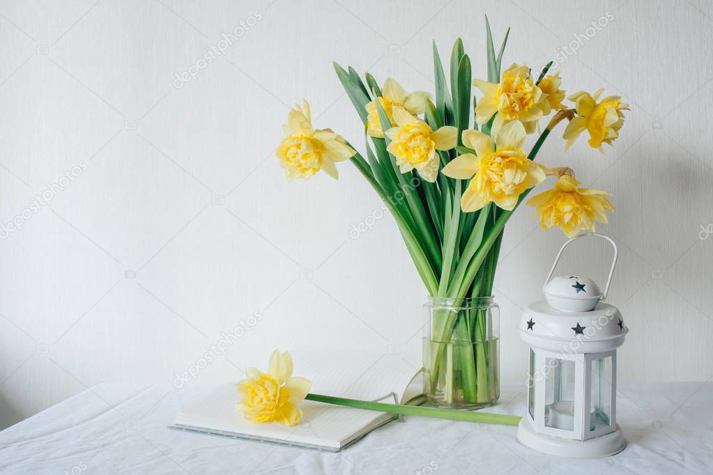 Yellow narcissus. Spring Flower. White notepad. Open notebook on white table. Stylish office. Place for entries. Place for the inscription. Bouquet of narcissus in a vase. Mother's day.