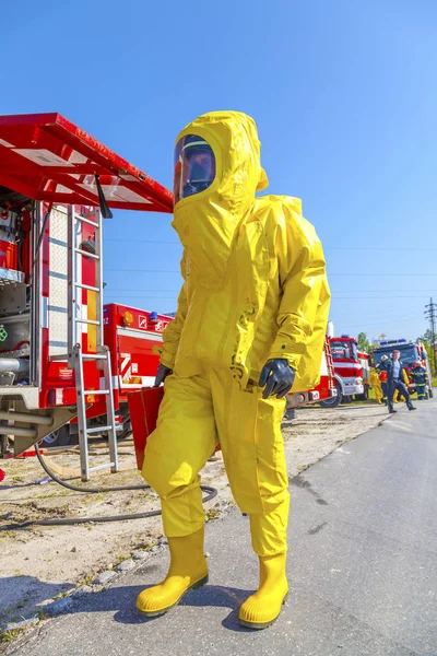 Az ember a sárga védő hazmat ruha, és a tűz teherautók — Stock Fotó