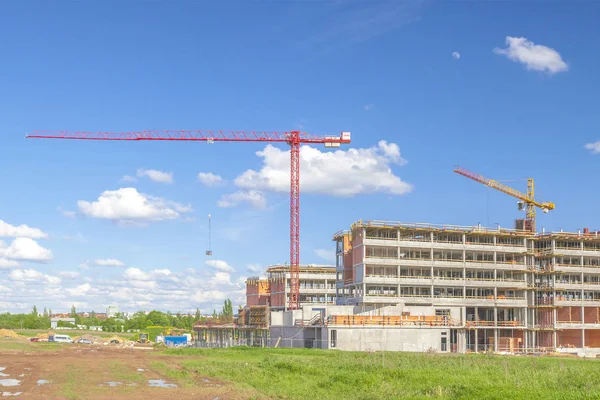 Byggnaden och kranar under konstruktion mot blå himmel — Stockfoto