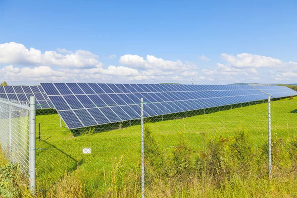 Solar energy panels on green field, blue sky — Stock Photo, Image