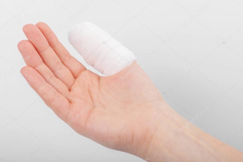 Injured finger with bandage on white background