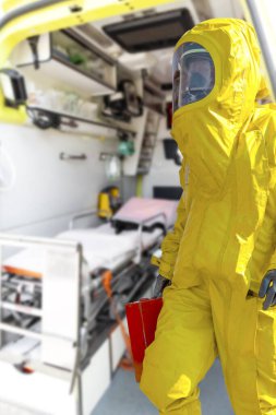 Ambulans ve ekipman içeriden görünüyor ve sarı koruyucu koruyucu koruyucu koruyucu koruyucu giysili adam. Salgın virüsü.