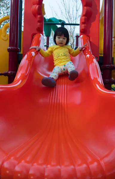 Sevimli Asya kız slayt üzerinde oynuyor 