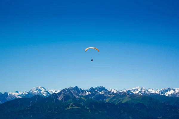 Gelber Gleitschirm über den europäischen Alpen Stockbild