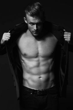 Erkek güzellik kavramı. Kot pantolon ve siyah arka plan üzerinde poz ceket giymiş şık saç kesimi ile şık genç adam portresi. Stüdyo vurdu