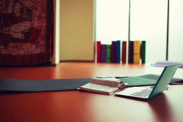 yoga room with big  light window in modern gym. yoga mat on the floor, computer and books.