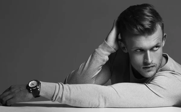 Advertising wrist watch concept. Beautiful (handsome) muscular male model with perfect body in grey jumper and with the clock on his hand. Street style.monochrome studio shot — Stock Photo, Image
