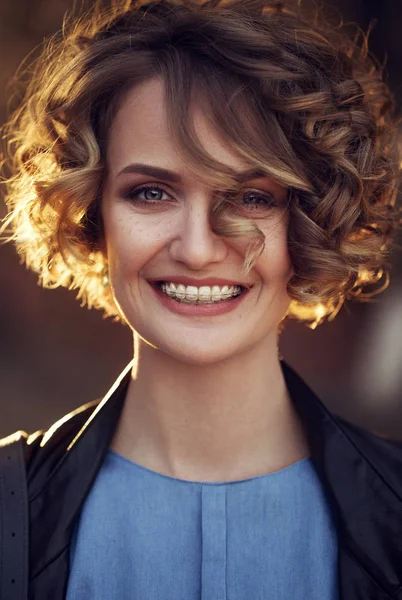 Beautiful blond teen girl with braces on her teeth smiling at the street on sunset — Stock Photo, Image