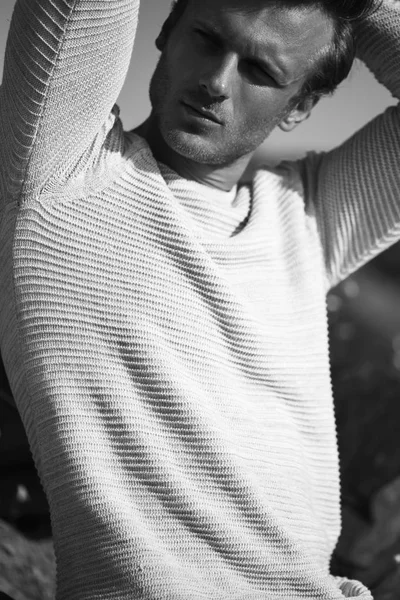 Concept de mode de rue. Portrait d'un jeune et beau homme en pull / pull blanc posant sur la nature et le fond rocheux. Ferme là. Plan de rue — Photo