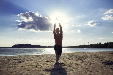 adam yoga uygulamaları ve sahilde spor pozisyonda derin derin düşünür