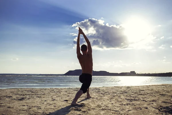 Man practices yoga and meditates in the sport position on the beach — Stock Photo, Image