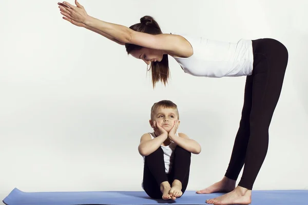 Madre e figlio fare yoga (esercizi sportivi), divertirsi e trascorrere un buon tempo insieme. isolato su bianco. il concetto di uno stile di vita sano — Foto Stock