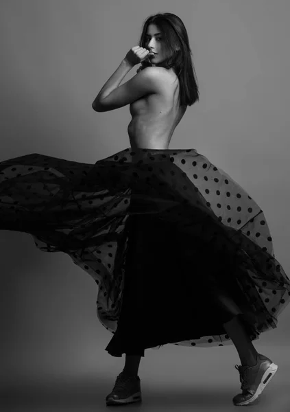 Концепция женской красоты. Портрет модной молодой девушки в черной юбке в горошек и кроссовки, позирующие на сером фоне. Перфект волос и кожи. Стиль Vogue. Студийный снимок Черно-белое (монохромное) фото — стоковое фото