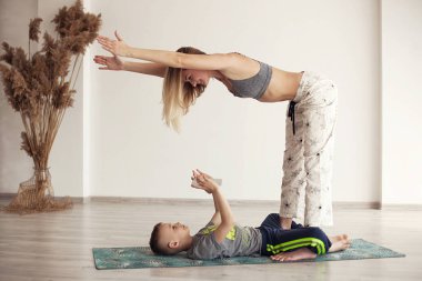 Anne ve oğlu evdeki karantinada yoga yapıyor (spor egzersizleri), eğleniyor ve birlikte iyi vakit geçiriyorlar. Beyaz üzerine izole edilmiş. Sağlıklı yaşam tarzı kavramı (COVID - 19)