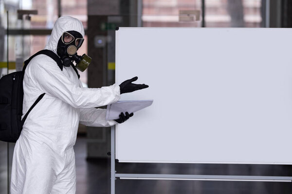 disinfector in a protective suit and mask shows the results of work on the board. The fight against coronovirus.