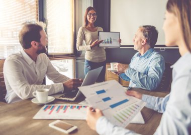 İş adamları ofisinde çalışıyor. Güzel genç iş kadını iş arkadaşları için sunum yapma, kullanma ve grafikleri açıklayan