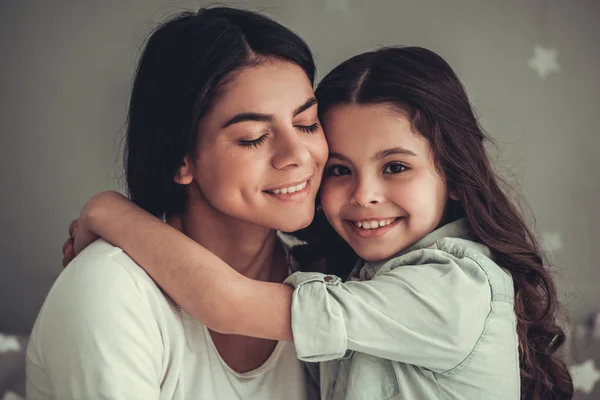 美丽的学校的女孩和她的妈妈是拥抱 微笑着坐在女孩的房间在家里 — 图库照片