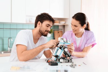 Adam mutfakta robot yapıyor. Onun kız arkadaşı onun yanındaduruyor ve ona yardım. Gülümse ve mutlu görün. Şık modern mutfak.