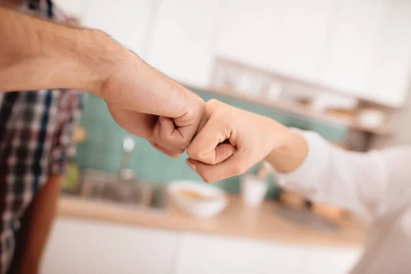 Greeting fist in a fist close-up. The guy and the girl in the kitchen. — Stock Photo, Image