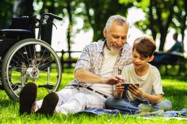 Yaşlı adam ve torunu pikniğe oturan ve bir şey de Smartphone'da arıyoruz