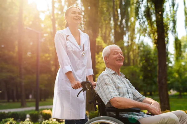 Läkare med gubbe i rullstol skrattar — Stockfoto