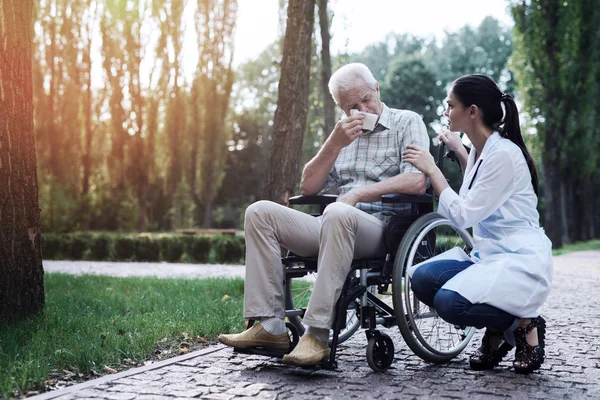 Läkaren hjälper gråtande gubben i rullstol — Stockfoto