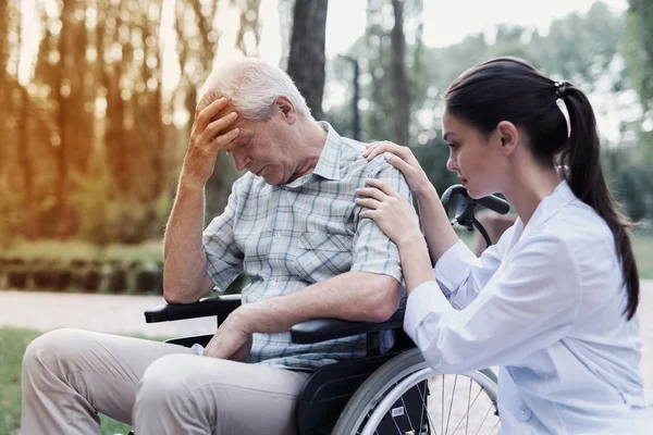 Tekerlekli sandalyede üzgün ihtiyar doktor yatıştırır — Stok fotoğraf