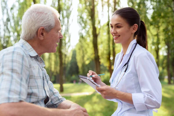 El doctor examina al viejo en el parque de verano. —  Fotos de Stock