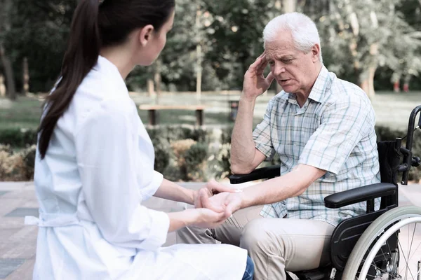 En äldre man i rullstol klagar över huvudvärk till en läkare — Stockfoto