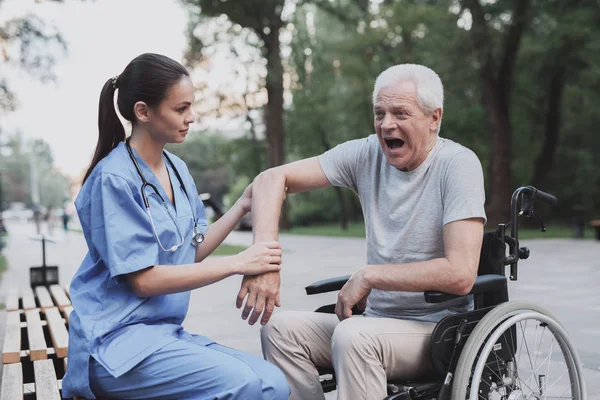 Den gamle mannen gav sjuksköterskan att undersöka hans armbåge som gör ont. — Stockfoto