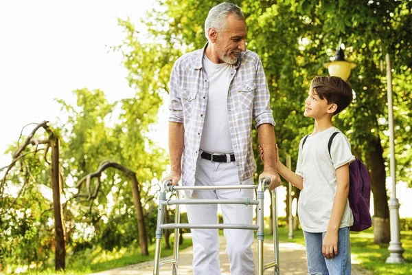 Un niño y un anciano en zancos para adultos están caminando en el parque — Foto de Stock