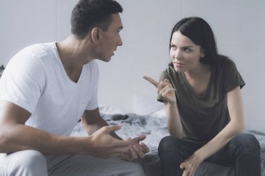 Kadın öfkeyle Puan bir parmak yanına yatağa oturup kendini haklı çıkarmaya çalışıyor adam