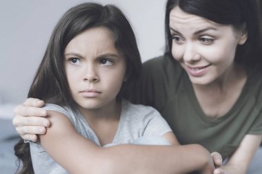 Kız ondan uzak döner ve yana doğru frowns kadın kız ve gülümsüyor, kucaklayan