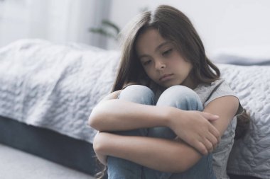 Esmer kız bacaklarını kollarını ile katta oturur ve ne yazık ki bir kenara görünüyor
