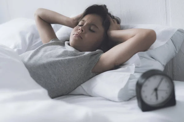 Una niña de pelo negro sosteniendo la cabeza debido a una fuerte alarma en la mañana — Foto de Stock