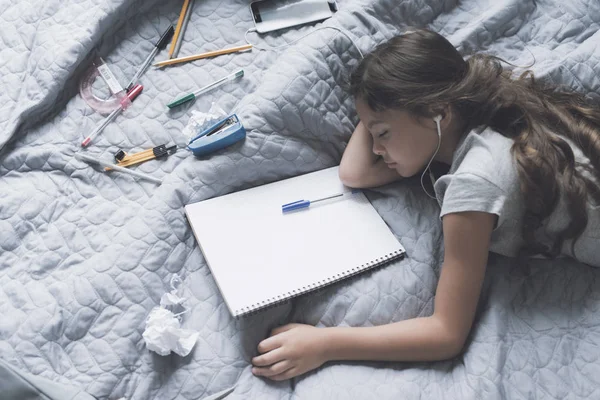 Fata cu părul negru a adormit pe un pat gri, ascultând muzică prin căști albe. — Fotografie, imagine de stoc