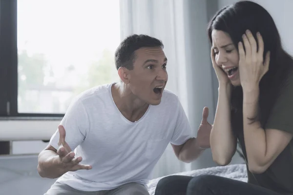 O homem de raiva grita para a mulher e ela em horror fecha os ouvidos com as mãos, de modo a não ouvir suas palavras — Fotografia de Stock